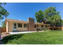 Spacious backyard featuring a well-maintained lawn, brick chimney, and concrete patio, perfect for outdoor enjoyment at 8228 Marshall Ct, Arvada, CO 80003