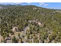 Expansive aerial view of a secluded home embraced by dense woodlands, offering privacy and natural beauty at 11421 Belle Meade Dr, Conifer, CO 80433