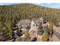 A beautiful exterior view of home showcasing its architectural details nestled between mature trees and snow at 11421 Belle Meade Dr, Conifer, CO 80433