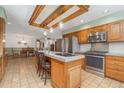 Traditional kitchen with stainless steel appliances, wood cabinets, tile floor, and a beamed ceiling at 10101 W 72Nd Ave, Arvada, CO 80005