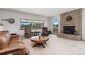 Bright living room features a fireplace, large windows with a backyard view, and comfortable seating at 10101 W 72Nd Ave, Arvada, CO 80005