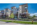 Modern townhome exterior featuring gray siding, balconies, green doors, and well-maintained front yards with wooden fences at 5654 N Emporia St, Denver, CO 80238