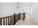 Bright hallway with wood floors, elegant chandelier, and staircase with wood railing at 6966 E 126Th Pl, Thornton, CO 80602