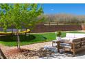 Spacious backyard featuring a cozy patio area with outdoor seating, a lush lawn, a trampoline, and beautiful landscaping at 7258 Oasis Dr, Castle Rock, CO 80108