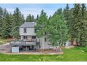 Backyard with a wooden deck, mature trees, and a well-maintained lawn, perfect for outdoor gatherings at 7614 Malamute Dr, Evergreen, CO 80439