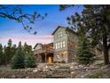 Inviting multi-story home with a stone base, complemented by a spacious wooden deck and mature trees at 1055 Divide View Dr, Golden, CO 80403