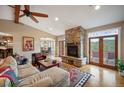 Open living room with stone fireplace, hardwood floors, ceiling fan, and access to outdoor deck at 1055 Divide View Dr, Golden, CO 80403
