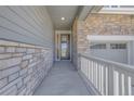 Covered front porch featuring stone columns and a white railing, leading to the front door at 8772 S Sicily Ct, Aurora, CO 80016
