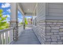 Covered front porch featuring stone columns and a white railing, offering a welcoming outdoor space at 8772 S Sicily Ct, Aurora, CO 80016