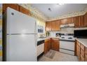 Small kitchen with wood cabinets, white appliances, and floral wallpaper at 3445 S Ammons St # 15-4, Lakewood, CO 80227