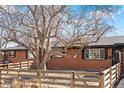 Beautiful brick home featuring a well-kept lawn, a sturdy fence, and a vibrant, mature tree at 5140 W 9Th Ave, Denver, CO 80204