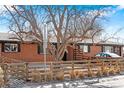 Brick home featuring a well-kept lawn and a sturdy fence, with mature trees providing shade at 5140 W 9Th Ave, Denver, CO 80204