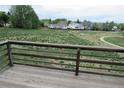 View from a wooden deck with railing overlooking an expansive grassy field and neighboring homes at 4812 S Bahama Way, Aurora, CO 80015