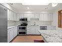 Bright kitchen featuring white cabinets, stainless steel appliances, and granite countertops at 7483 W Cedar Cir, Lakewood, CO 80226