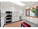 Bright kitchen with white cabinets, stainless steel appliances, granite counters and a skylight at 7483 W Cedar Cir, Lakewood, CO 80226