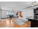Open living room with hardwood floors, white sectional sofa, and adjacent dining area at 1551 Larimer St # 1106, Denver, CO 80202
