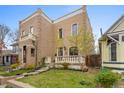 Charming brick home with a front porch, lush green lawn, and blooming trees at 2330 N Emerson St, Denver, CO 80205