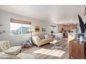 Sun-filled living room with wood floors and large windows offering views of the exterior at 12705 Ulster St, Thornton, CO 80602