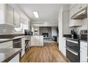Open kitchen view with stainless steel appliances, white cabinets, breakfast bar, and stone fireplace in view at 8746 Sunridge Hollow Rd, Parker, CO 80134