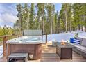 Outdoor deck with a hot tub, a cozy fire pit, and seating surrounded by serene woods for ultimate relaxation at 100 Apache Rd, Evergreen, CO 80439