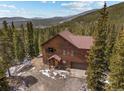 Aerial view of a rustic log cabin home nestled in a lush forest with a driveway in the mountains at 72 Overlook Ct, Idaho Springs, CO 80452