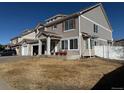 Tan two-story house featuring an attached garage, porch, and well-kept lawn on a sunny day at 21561 E 48Th Pl, Denver, CO 80249