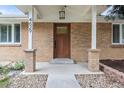 Inviting front porch with brick columns and a wooden front door at 4629 Estes St, Wheat Ridge, CO 80033