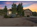 Charming home with a two-car garage, complemented by lush trees and colorful sunset at 5285 E State Highway 86, Franktown, CO 80116