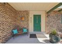 Inviting front porch with a bright green door, brick accents, and a cozy bench with decorative pillows at 6121 W 108Th Ave, Westminster, CO 80020