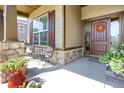 Inviting front porch with stone columns, cozy seating, and a decorative wreath on the front door at 3419 Traver Dr, Broomfield, CO 80023