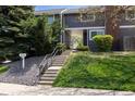 Inviting entrance to gray condo with lush landscaping, steps leading to front door and mailbox at 6730 W 84Th Cir # 96, Arvada, CO 80003