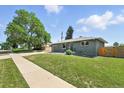 Well-manicured lawn and attractive gray exterior complemented by mature trees at 2714 S Raleigh St, Denver, CO 80236