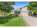 Inviting home exterior with a lush green lawn, mature trees, and a two-car garage at 4932 Democrat Dr, Broomfield, CO 80023