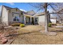 Landscaped front yard featuring a stone-accented home with covered front porch and mature tree at 4932 Democrat Dr, Broomfield, CO 80023