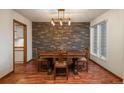Traditional dining room boasts stone accent wall, wood floors, and a decorative light fixture at 1585 W Briarwood Ave, Littleton, CO 80120