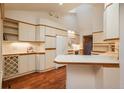 Bright kitchen with white cabinets, skylight, tiled countertops and backsplash, and wood-look floors at 1585 W Briarwood Ave, Littleton, CO 80120