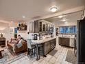 Open-concept kitchen features custom cabinetry, stainless steel appliances, and breakfast bar seating with tile floors at 40 Benton St, Lakewood, CO 80226