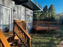 View of the back porch and stairs leading to a well-maintained grassy yard surrounded by trees at 9288 Krashin Dr, Conifer, CO 80433
