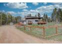 Charming grey home featuring a fenced yard, wooden deck, and lovely surroundings on a sunny day at 9288 Krashin Dr, Conifer, CO 80433