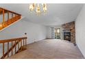 Bright living room featuring a stone fireplace, carpeted floor, and a wooden staircase at 12043 E Ford Cir, Aurora, CO 80012