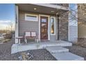 Charming front porch with seating, a red door, and stone accents for a welcoming entryway at 15878 E Broncos Pl, Englewood, CO 80112