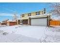 Traditional two-story home with brick and siding exterior, featuring a two-car garage and a snow-covered front yard at 8694 E Eastman Ave, Denver, CO 80231