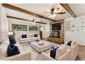 Bright living room featuring exposed wood beams, a brick fireplace, and plush seating with blue accents at 12408 E Ohio Ave, Aurora, CO 80012