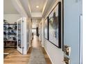 Bright hallway showcasing modern lighting, hardwood floors, elegant artwork, and an open view into other living spaces at 13812 Honey Hush Trl, Parker, CO 80134