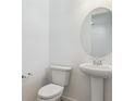 Powder room featuring a pedestal sink, modern faucet, round mirror and a toilet at 8295 Snake River St, Littleton, CO 80125