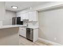 Modern kitchen with white cabinets, stainless steel appliances, quartz countertops, and light-colored hardwood floors at 381 S Ames St # E104, Lakewood, CO 80226