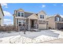 Charming two-story home with stone accents, an attached two-car garage, and snow-covered front yard at 16278 E 111Th Pl, Commerce City, CO 80022