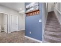 Inviting entryway with gray walls, decorative wall art, coat hooks and a carpeted staircase leading to the upper level at 11250 Florence St # 30B, Commerce City, CO 80640