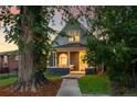 Inviting home featuring a brick facade, a covered porch, and mature trees in the front yard at 2515 Zenobia St, Denver, CO 80212