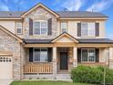 Charming home featuring a stone and tan exterior, a covered front porch, and decorative shutters at 2463 Tavern Way, Castle Rock, CO 80104